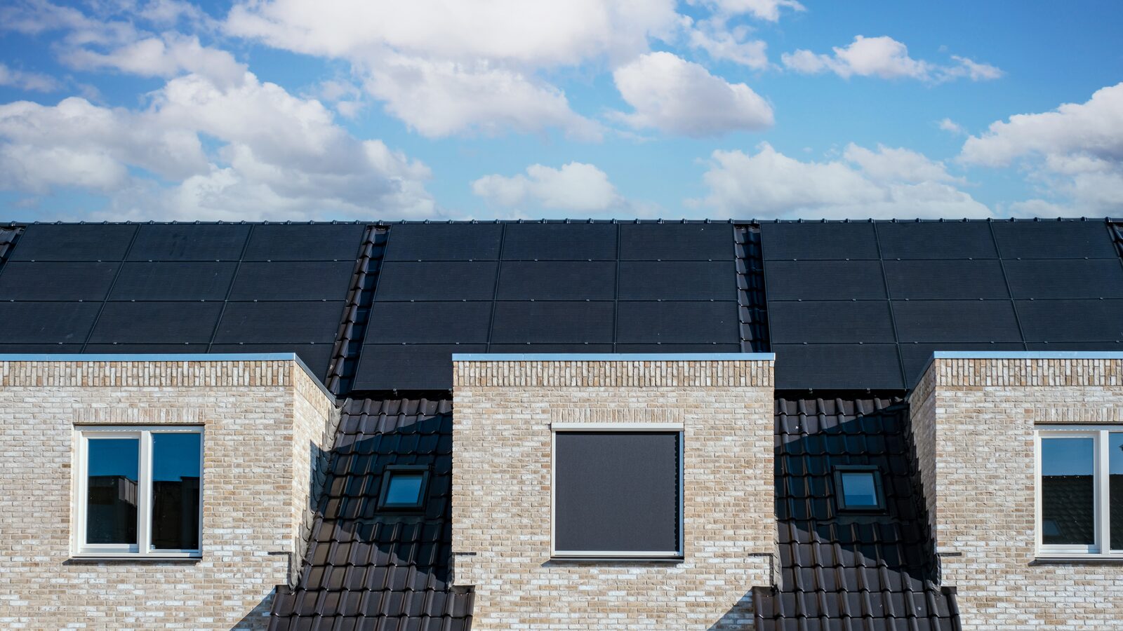 Rijtjeshuizen met een dak vol strak gelegde zwarte zonnepanelen